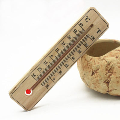 Wooden thermometer leaning on pottery with red indicator