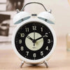 White retro twin bell alarm clock on wooden surface