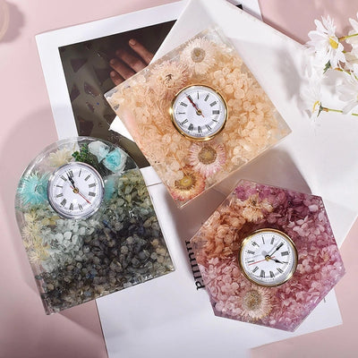 Three geometric resin table clocks with floral designs.