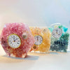 Three colorful resin clocks with floral designs.